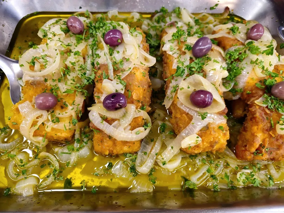Pavés de morue panés, oignons et olives